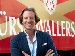 Carl-Eugen Prinz zu Oettingen-Wallerstein steht vor einem roten Fürst Wallerstein LKW