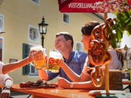 Junge Menschen sitzen am Biertisch und prosten sich zu